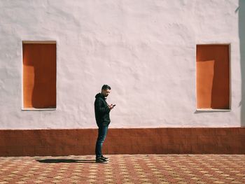 Full length of young man standing against window on building