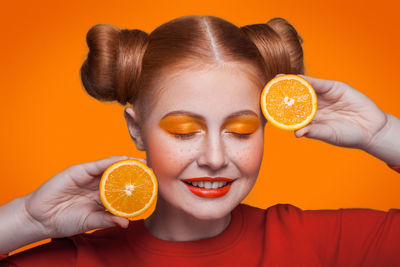 Portrait of woman holding apple against orange background