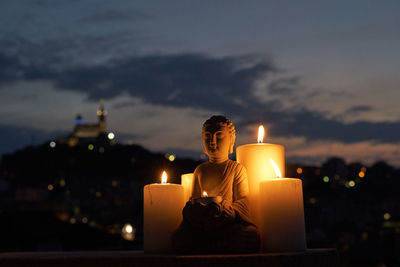 Lit tea light candles against sky at night