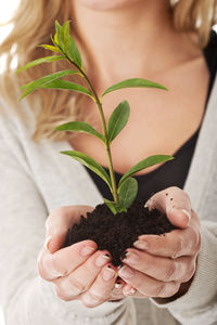 Midsection of woman holding plant against white background