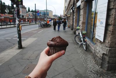 Hand holding ice cream on street