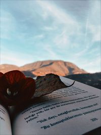 Close-up of open book on mountain against sky