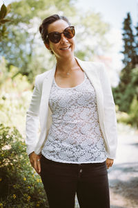 Happy young asian woman in blazer and sunglasses smiling