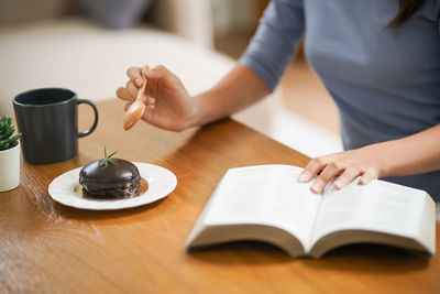 Midsection of woman writing in book at table