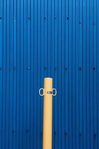 Beige pole against blue corrugated iron