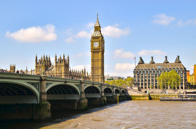 Arch bridge over river and buildings against sky in city