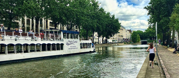 Rear view of people on canal by trees