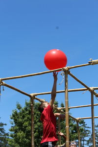 Rear view of man playing with balloons against blue sky