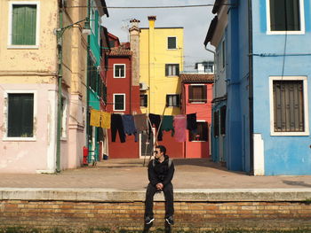 Full length of man sitting against buildings