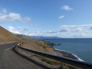 Scenic view of road by sea against sky