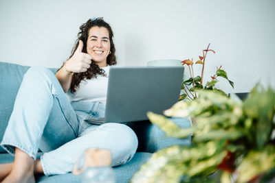 Young woman using laptop on sofa at home