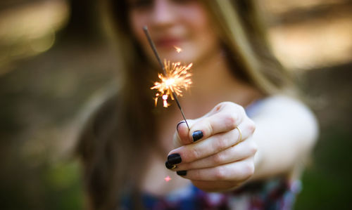 Cropped image of woman holding lit sparkler