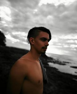 Portrait of shirtless man in sea against sky