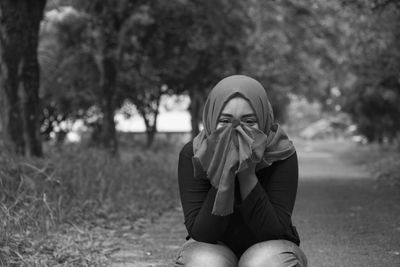 Portrait of young woman in hijab covering face