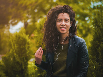 Portrait of young woman listening to music by plants