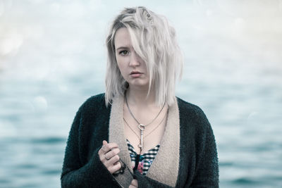 Portrait of beautiful woman holding sunglasses against blurred background