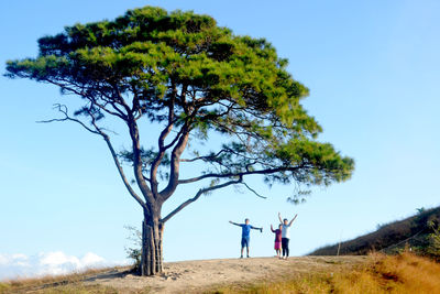 Man and woman standing on field against clear blue sky