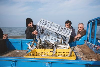 Group of people having food in sea against sky