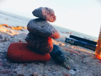 Close-up of stone stack on rock at beach against sky