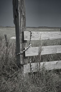 Close-up of wooden post on field against sky