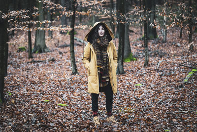Natural young woman stands empowered and alone in autumn forrest