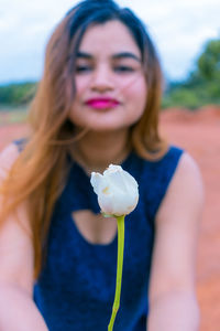 Portrait of beautiful woman holding red flowering plant