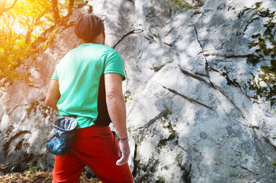 Athletic middle aged male climber stands in front of a large training rock before free 