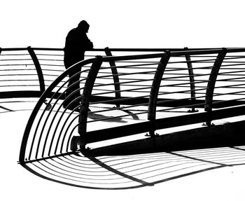 Silhouette man standing on railing against sky