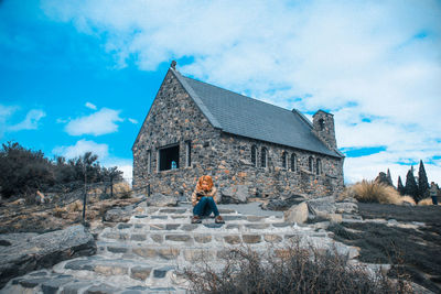 Woman standing by building against sky