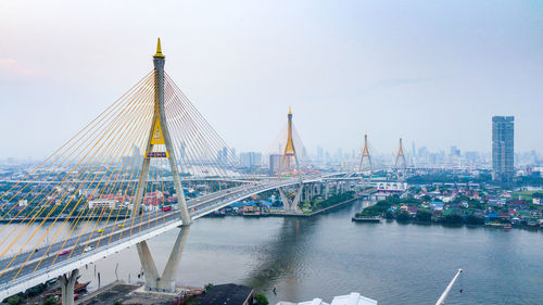 Bridge over river in city against sky