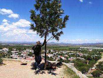 Man standing by tree against sky in city