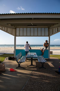 People sitting by sea against sky