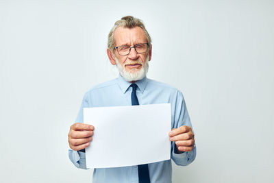 Senior man holding paper against colored background