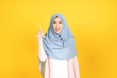 Young woman wearing mask against yellow background