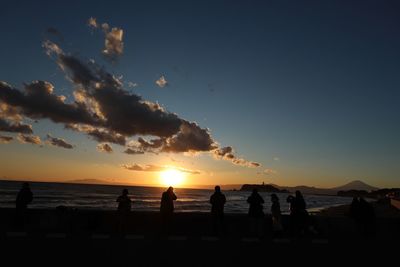 Silhouette people on beach against sky during sunset