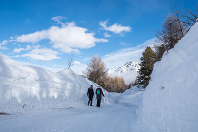 Rear view of friends walking on snow covered landscape