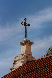 Low angle view of cross on roof of building against sky