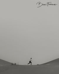 Man walking on field against clear sky