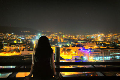 Rear view of woman standing in city at night