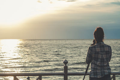 Rear view of girl standing by sea