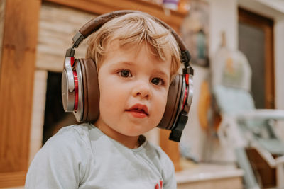 Cute boy listening music through headphones at home