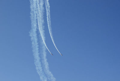 Low angle view of airshow in clear blue sky
