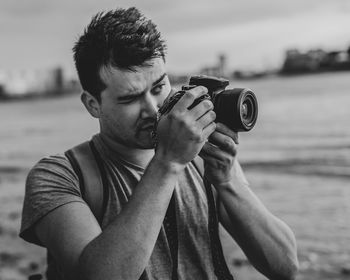 Midsection of man holding camera while standing outdoors