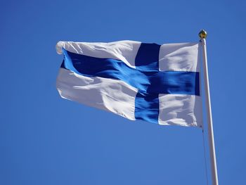 Low angle view of finnish flag waving against clear blue sky