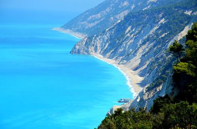 High angle view of sea and mountains against blue sky