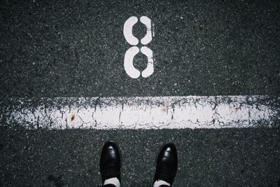 Low section of man standing by number 8 on road