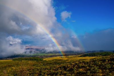 Scenic view of rainbow over landscape against sky