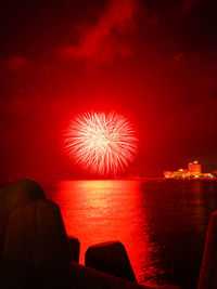 Firework display over sea against sky at night