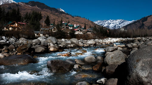 Scenic view of river by snowcapped mountains against sky