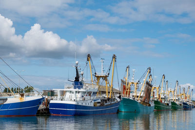 Fishing boats moored at harbor against sky